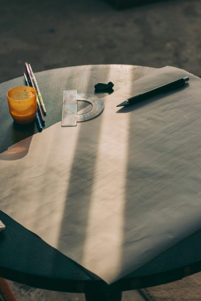 Sunlit table with drawing paper, pencils, and art tools for creativity.